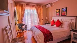a bedroom with a bed with red pillows and a window at A&A Guesthouse in Port Elizabeth +99 photos
