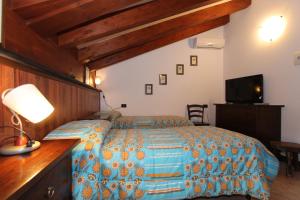 een slaapkamer met een bed, een bureau en een televisie bij Albergo Santo Spirito in Molini di Triora