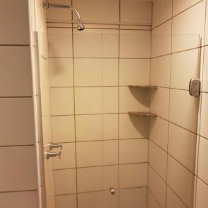 Un baño con ducha con azulejos blancos. en Beach Class Residence Service, en Fortaleza