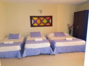 three beds in a room with a painting on the wall at Hotel Tumburagua Inn Ltda in Neiva