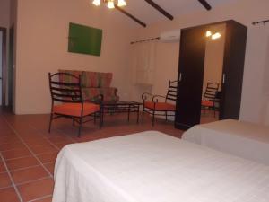 Habitación con 2 camas, sillas y mesa. en Casa Rural "La Posada de María", en Malpartida de Cáceres