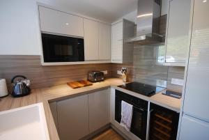 uma cozinha com armários brancos e um forno de fogão preto em The Beeches Holiday Cottage em Auchterarder
