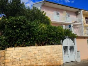 una casa rosa con una puerta blanca y una valla en Apartments Katnić, en Hvar