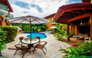 a patio with a table and umbrella next to a pool at Hotel Villa Di Rimini in Ubatuba