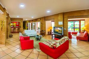 sala de estar con muebles de color rojo y TV de pantalla plana en Hotel Villa Di Rimini, en Ubatuba