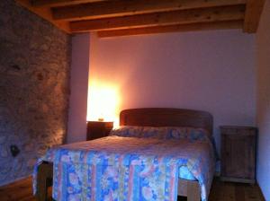 a bedroom with a bed and a lamp on a wall at Maison de caractère en Pierre Cal Blanic in Saint-Pierre-dels-Forcats