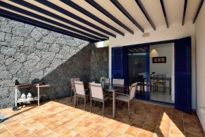 a patio with a table and chairs and a stone wall at Villa Yucas in Playa Blanca