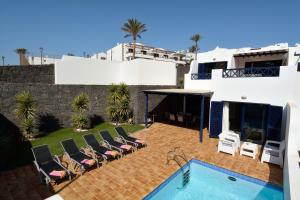 - une piscine en face d'une maison avec des chaises dans l'établissement Villa Yucas, à Playa Blanca