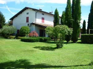 biały dom z czerwonymi oknami na dziedzińcu w obiekcie Cascina Maria w mieście Desenzano del Garda