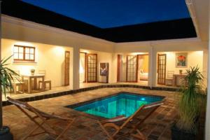 a swimming pool in a house with two chairs at Baleia Guest Lodge in Hermanus