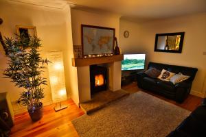 uma sala de estar com lareira e televisão em Picturesque Village House em Aghnablaney