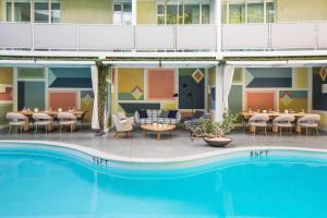 uma piscina em frente a um hotel com mesas e cadeiras em Avalon Hotel Beverly Hills, a Member of Design Hotels em Los Angeles