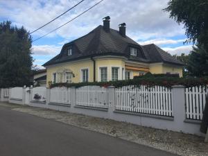 ein gelbes Haus mit weißem Gartenzaun in der Unterkunft Haus in idyllischer Lage in Wien