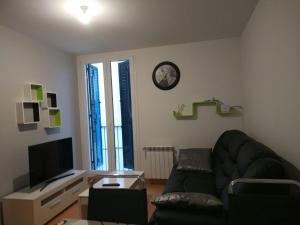 uma sala de estar com um sofá e um relógio na parede em Apartamento Carmen em Pamplona