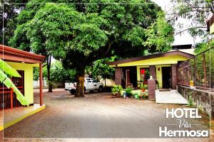 dom z drzewem przed nim w obiekcie Hotel Villa Hermosa w mieście Liberia