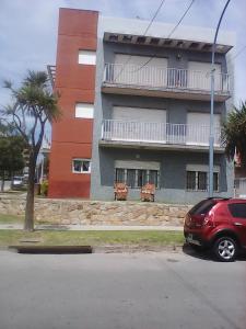 um carro vermelho estacionado em frente a um edifício em MOGOTES FLAT FRENTE AL MAR em Mar del Plata