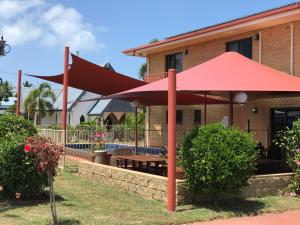 um guarda-chuva vermelho em frente a uma casa em Kurrimine Beach Motel em Kurrimine Beach