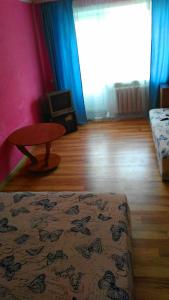 チタにあるул.Ленина д.25のベッドとテーブル付きの部屋、青いカーテン付きの部屋