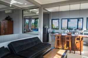a living room with a black couch and a kitchen at Jiwa's House in Ubud