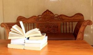 a stack of books on a wooden table with a bench at Lucky Family Villa in Ubud