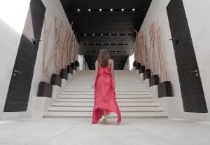 a woman walking down the stairs in a pink dress at eqUILIBRIA Seminyak - CHSE Certified in Seminyak