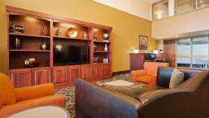 a living room with orange chairs and a flat screen tv at Best Western Executive Inn Kenosha - Pleasant Prairie in Kenosha