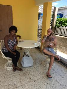 two women and a man sitting on chairs in front of a table at Leslies' Home in Portmore