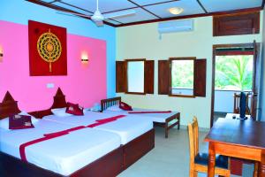 een slaapkamer met 2 bedden en een tafel en een roze muur bij The Triangle Hotel in Anuradhapura