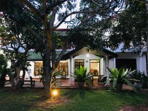 a white house with a tree in the yard at Pearl House Resort in Anuradhapura