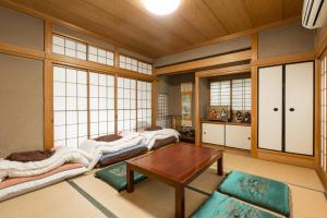 een kamer met drie bedden en een tafel erin bij Calligraphy House in Kyoto