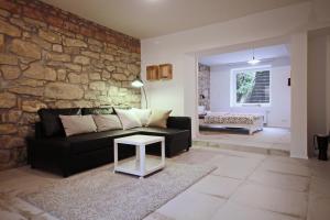 a living room with a black couch and a stone wall at Apartment Kosatcová in Prague