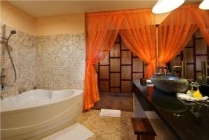 an orange bathroom with a tub and a sink at Jungle Retreat by Kupu Kupu Barong in Ubud +35 photos