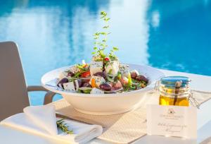 a salad in a bowl on a table next to a pool at Caravia Beach Hotel in Marmari
