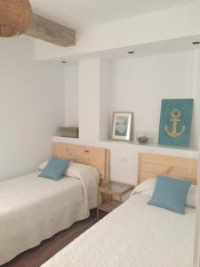 ログローニョにあるG&D Vivienda Turísticaの白い壁の客室で、ベッド2台、青い枕が備わります。