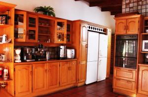 uma cozinha com armários de madeira e um frigorífico branco em House on York em Joanesburgo