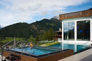 a house with a swimming pool with mountains in the background at Hotel Goldried in Matrei in Osttirol