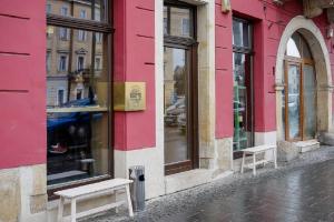 een roze gebouw met twee banken in een straat bij Vinodorum Apartments in Cluj-Napoca