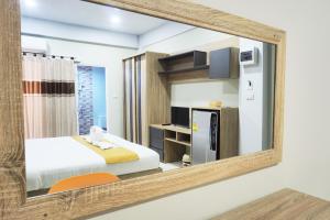 um espelho que reflecte um quarto com uma cama e um frigorífico em Supreme Place SHA Plus em Khon Kaen