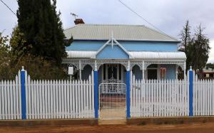 a blue and white house with a white fence at Ella's Place in Broken Hill