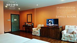 a bedroom with a bed and two chairs and a tv at The Brown House Hotel in Chachoengsao