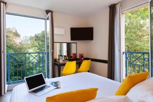 a room with a laptop on a table with a balcony at Best Western Hotel du Chateau Maisons Laffitte in Maisons-Laffitte