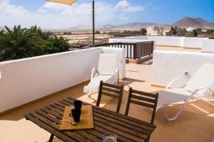 Un balcón con una mesa y sillas en un tejado. en Casa Maui, en La Oliva