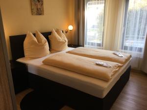 1 dormitorio con 2 camas con sábanas blancas y ventana en Villa Sudrow, en Bad Reichenhall