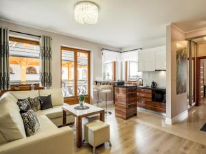 a living room and kitchen with a couch and a table at TatryTop Zakopiańskie Tarasy Premium & SPA in Zakopane
