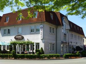 un gran edificio blanco con techo rojo en Hotel Ammerländer Hof, en Westerstede