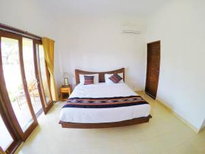 una camera da letto con un letto grande in una stanza con finestre di Pandawa Lembongan Homestay a Nusa Lembongan