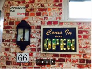 a brick wall with a sign and a sign that says come up we are open at West Cromwell Hotel in London