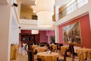 a restaurant with tables and chairs and a large painting at Hotel Maxim in Anzola dell'Emilia