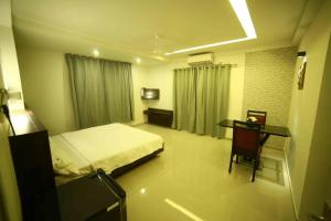 1 dormitorio con 1 cama y escritorio con silla en Nalanda Inn, en Palakkad