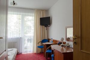 a hotel room with a bed and a desk and a window at Hotel Nidzki in Ruciane-Nida